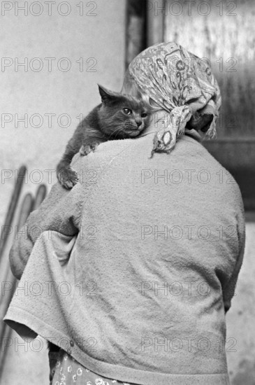Cat on a farmer's shoulder on a former Franconian farm, black and white, Bavaria, Germany