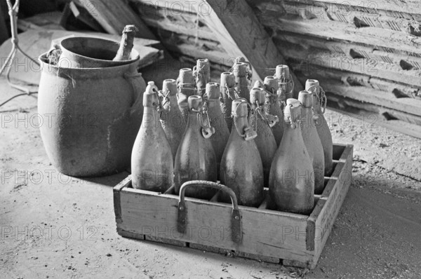 Old wooden beer crate with beer bottles from the 1940s in the attic, on a former Franconian farm, black and white, Bavaria, Germany