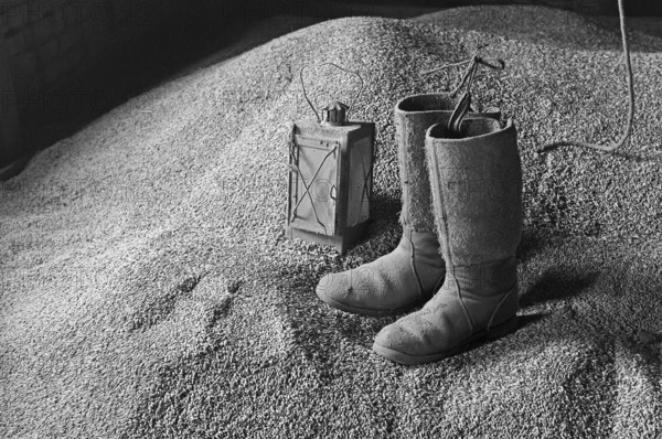 Old stable lantern and felt boots on the grain floor, on a former Franconian farm, black and white, Bavaria, Germany