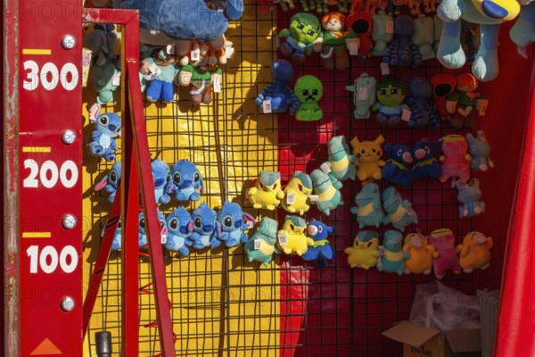 Close-up of blue, yellow and green plush prize dolls at game kiosk at Fun Show traveling ride park, Old Port of Montreal, Quebec, Canada