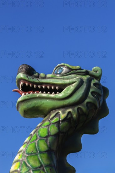 Green dragon with big teeth and long red tongue against blue sky background, Fun Show traveling amusement ride park, Old Port of Montreal, Quebec, Canada