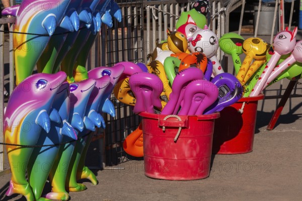 Red plastic buckets with colorful balloons in unusual shapes including cats etc, and dolphins in a row at Fun Show traveling amusement ride park, Old Port of Montreal, Quebec, Canada