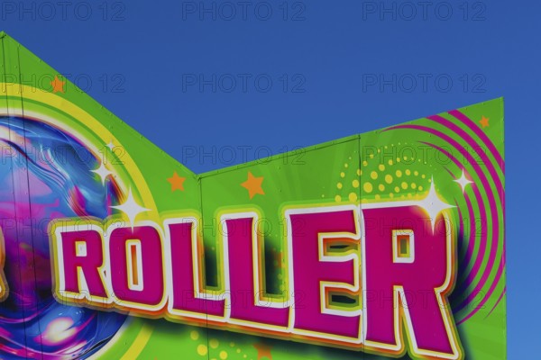Close-up of the word Roller painted in purple fluorescent paint on banner at Fun Show traveling amusement ride park, Old Port of Montreal, Quebec, Canada