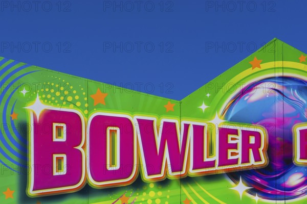 Close-up of the word Bowler painted in purple fluorescent paint on banner at Fun Show traveling amusement ride park, Old Port of Montreal, Quebec, Canada