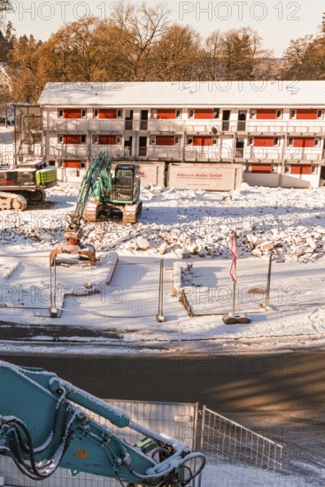 Construction work in front of a snowy building with excavator and equipment in the foreground, Nagold, Calw district, Black Forest, Germany
