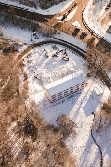 Construction work on a snowy area next to a road and a building, Nagold, Calw district, Black Forest, Germany