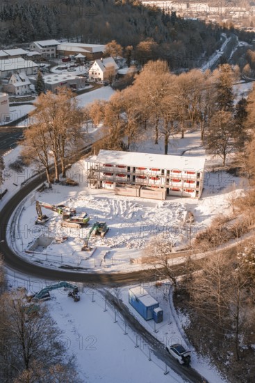 Snow-covered construction site with heavy equipment, surrounded by winter trees seen from the air, Nagold, Calw district, Black Forest, Germany