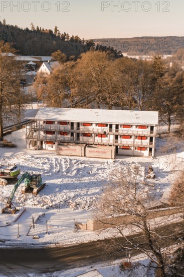 Construction site of a building in snow surrounded by trees and hilly landscape, Nagold, Calw district, Black Forest, Germany