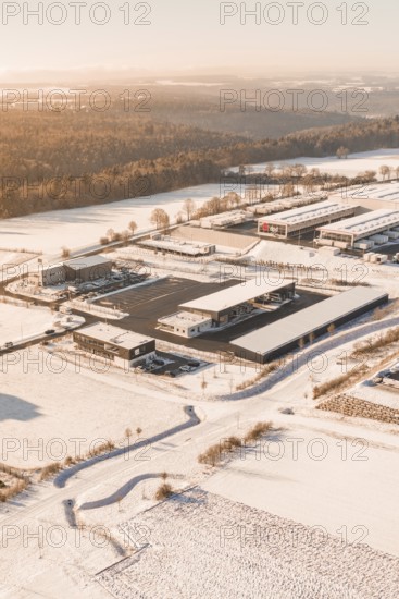 Snowy industrial landscape at sunset surrounded by fields and trees, Nagold, Calw district, Black Forest, Germany