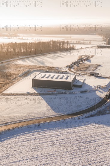 Warehouse in snowy landscape with surrounding roads and forests at sunset, Nagold, Calw district, Black Forest, Germany
