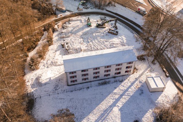 Building on construction site in the forest, surrounded by snow and cranes in a wintry atmosphere, Nagold, Calw district, Black Forest, Germany