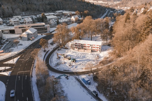 Snow-covered construction site and roads with a view of a wintry settlement and forest, Nagold, Calw district, Black Forest, Germany