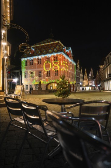 Evening scene with illuminated historic building and empty café chairs in the foreground, Nagold, Calw district, Black Forest, Germany