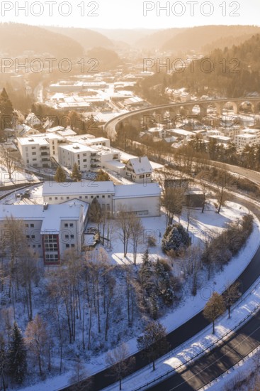 Residential building in a snowy urban landscape with roads and a bridge, surrounded by hills, Nagold, Calw district, Black Forest, Germany