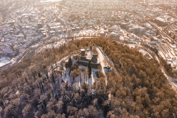 Aerial view of a snowy castle surrounded by a forest, with a city in the background at sunrise, Nagold, Calw district, Black Forest, Germany