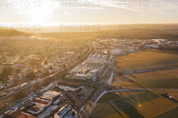 Urban landscape with industrial buildings in bright morning light, fields stretching into the distance, Althengstett, Calw district, Germany