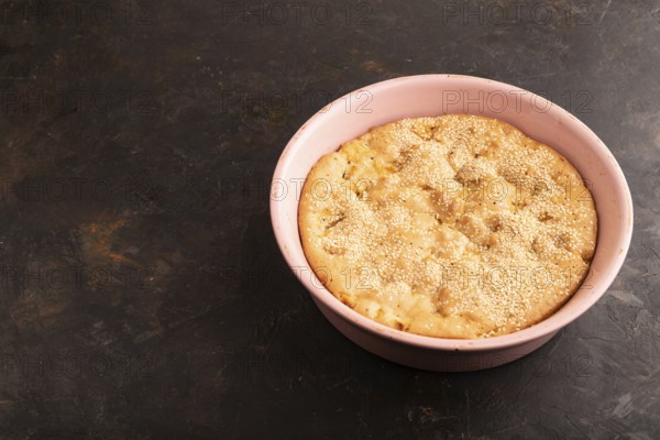 Apple Charlotte cake in baking dish on black concrete background, side view, copy space
