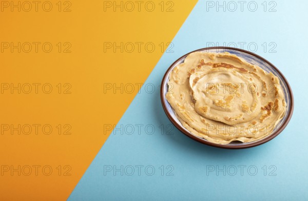Stack of Plain Fried pancakes on blue and orange pastel paper background. side view, copy space