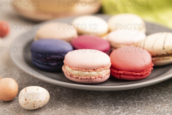 Macarons colourful cookies dessert, cup of coffee, on brown concrete background with green linen textile, close up, side view, selective focus