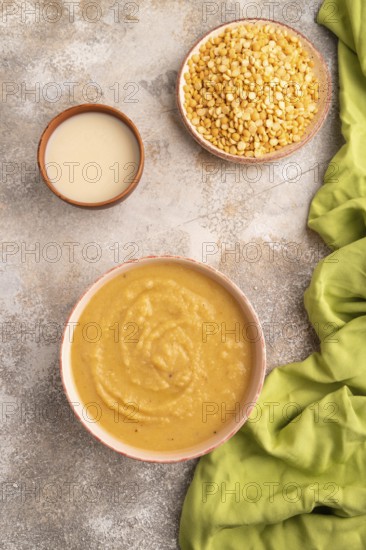 Pea cream soup, Puree, porridge in ceramic bowl on brown concrete background and green linen textile. Diet, healthy eating concept. top view, flat lay, close up, minimalism