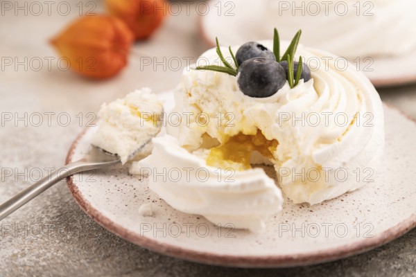 Pavlova Meringue dessert with crisp meringue and blueberry, cup of coffee, on brown concrete background with green linen textile, close up, side view, selective focus