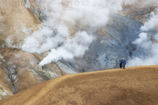 Two tourists walking in the geothermal area of Hveradalir, part of the active Kerlingarfjöll volcanic system, along the F35 Kjölur (Kjalvegur) route, Central Highlands, Iceland