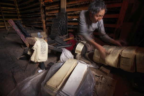 A Tibetan prints the pages of sacred religious texts at the historic Tibetan Buddhist printing houses of Palpung Monastery (Palpung Gompa), located in the village of Babang, Dêgê (Derge) County, Garzê Tibetan Autonomous Prefecture, Sichuan Province, Eastern Tibet, China, Asia