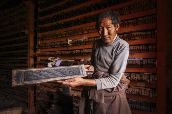A Tibetan shows the printing block for sacred religious texts at the historic Tibetan Buddhist printing houses, Palpung Monastery (Palpung Gompa), in the village of Babang, Dêgê (Derge) County, Garzê Tibetan Autonomous Prefecture, Sichuan Province, Eastern Tibet, China, Asia