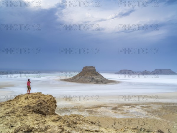 A tourist admires the inselbergs Karamaya and the Three Brothers (Three Batyrs), the Karagiye Depression with its salt lake (Kendirli Sor) on the ancient Tethys Ocean floor, Karyn Zharyk, Ustyurt Reserve, Mangystau, Kazakhstan, Asia