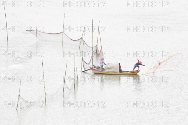 Woman and man in a small boat fishing with a net in Xiapu, Fujian Province, along the East China Sea, China, Asia