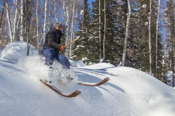 Skier with long traditional wooden skis and a long pole in the Altai Mountains, possibly the birthplace of skiing, Altai Prefecture, Xinjiang Uygur Autonomous Region, Northwest China, Asia
