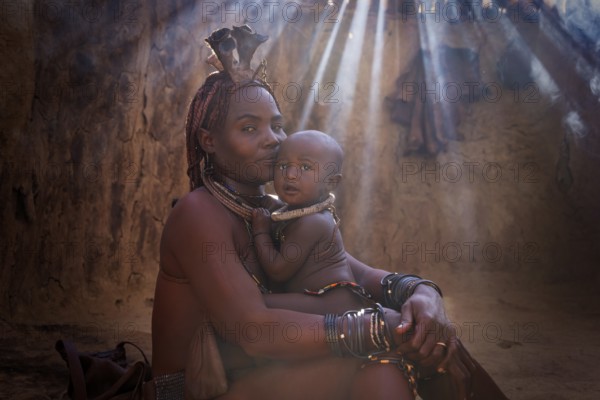 Ovahimba or Himba woman with a baby inside traditional hut, Kaokoland, Kunene Region, Namibia