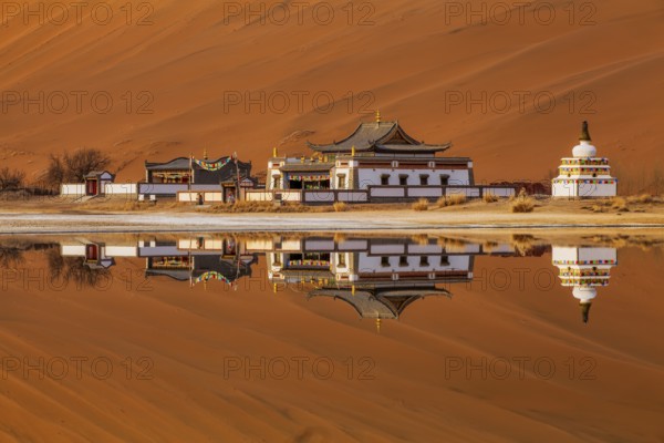 Reflection of Badain Jaran Temple by the shore of a lake, Tibetan-Buddhist temple, Badain Jaran Desert, Inner Mongolia Autonomous Region, China, Asia