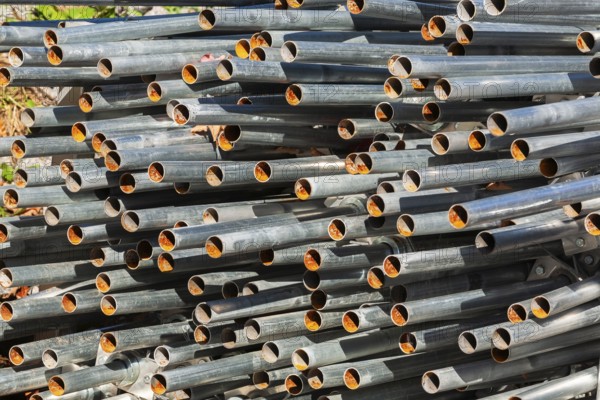 Close-up of stacked heavy duty galvanized steel poles in outdoor storage yard in early autumn, Quebec, Canada