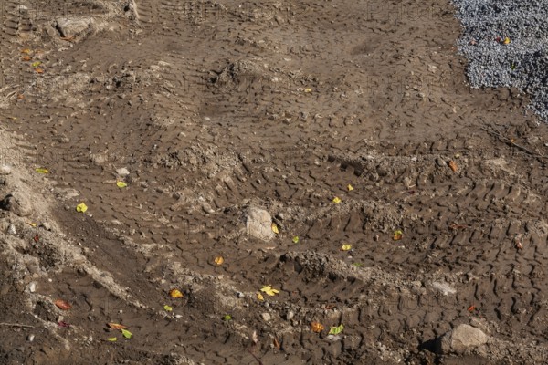 Deep tire tracks made by earth loader in light brown wet sand at construction site in early autumn, Quebec, Canada