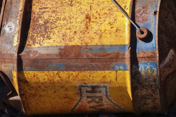 Close-up of discarded old rusted yellow and blue Irving Oil gas container laying on its side outdoors in early autumn, Quebec, Canada