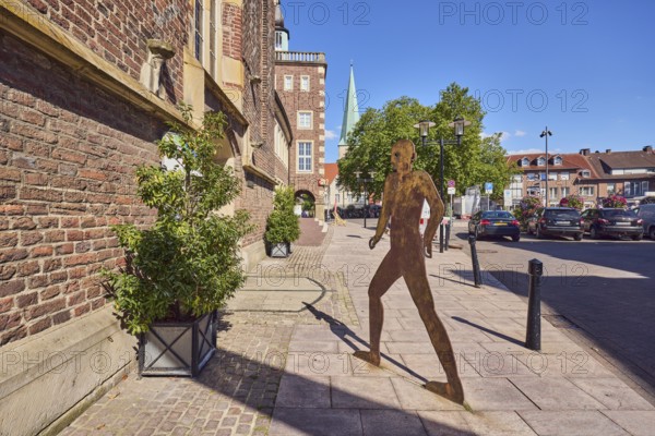Brick building, façade, historic town hall, masonry, sculpture of a person silhouette, barrier bollards, parking boxes with cars, plant pots, trees, blue sky, cloudless, Heilig-Geist-Straße, marketplace, market, Borken, Münsterland, Borken district, North Rhine-Westphalia, Germany