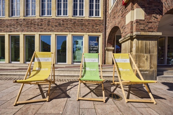Sun loungers with inscription, Das gute Leben in Borken, Münsterland. The Good Life, FARB - Forum Altes Rathaus Borken, historic town hall, brick building, façade with windows, city museum, tourist information, cultural office, walkway made of natural stone slabs, frog's eye view, sunny, Borken, Münsterland, Borken district, North Rhine-Westphalia, Germany