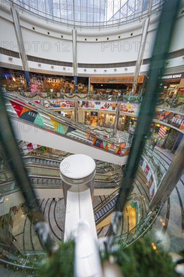 Lively interior of a shopping mall with several escalators and colorful shops, London, England, Great Britain