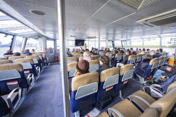 Interior view of a boat with many seated passengers and modern seats, London, England, Great Britain