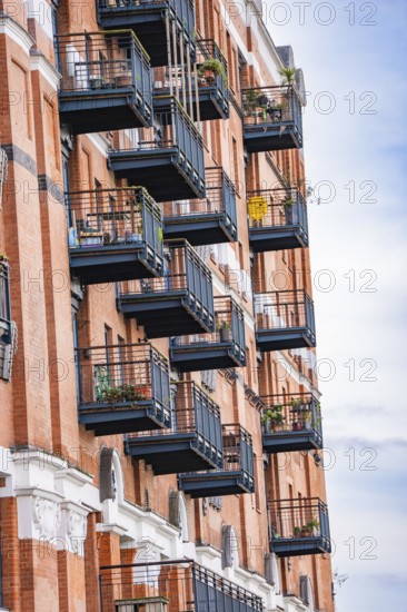 A building with numerous balconies and brick façade in an urban setting, London, England, Great Britain