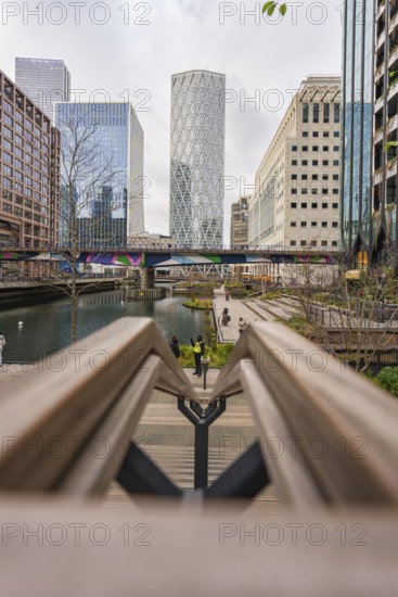 Modern buildings on a waterway with a bridge and sidewalks in the foreground, Canary Wharf, London, England, Great Britain
