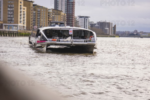 A river with tall modern buildings on its banks, with a ship in the foreground, London, England, Great Britain