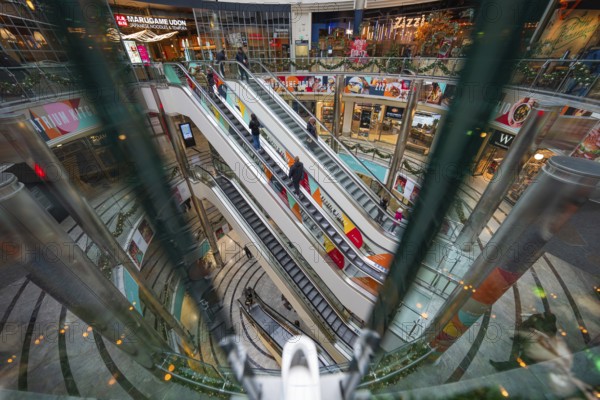 Colourful escalators in a multi-storey shopping mall with a lively atmosphere, London, England, Great Britain