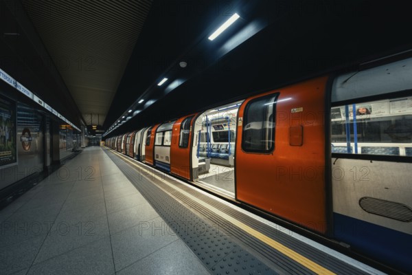 A subway train with doors open stands in the station while the lights animate the station, London, United Kingdom