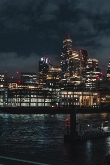 Urban skyline at night with illuminated skyscrapers and reflections in the river, London, England, Great Britain