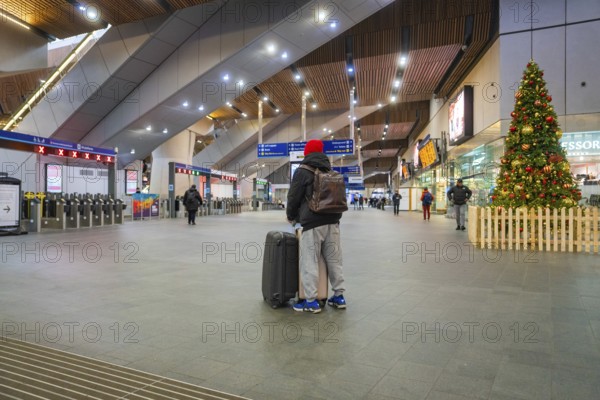 A traveler in a train station with luggage surrounded by modern architecture and Christmas decoration, London, England, Great Britain