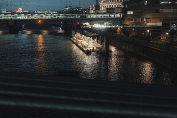 Urban river view at night with reflecting city lights in water, London, England, Great Britain