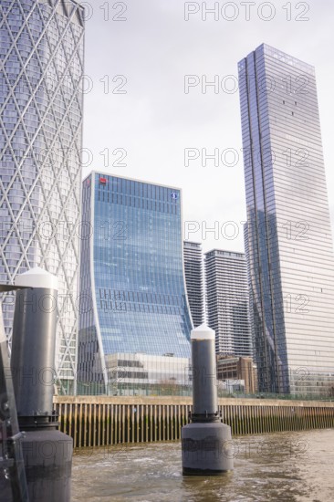 Skyscrapers with glass façade on a river under cloudy sky in the city, London, England, Great Britain