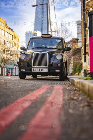A black taxi against the backdrop of The Shard in London, London, England, Great Britain